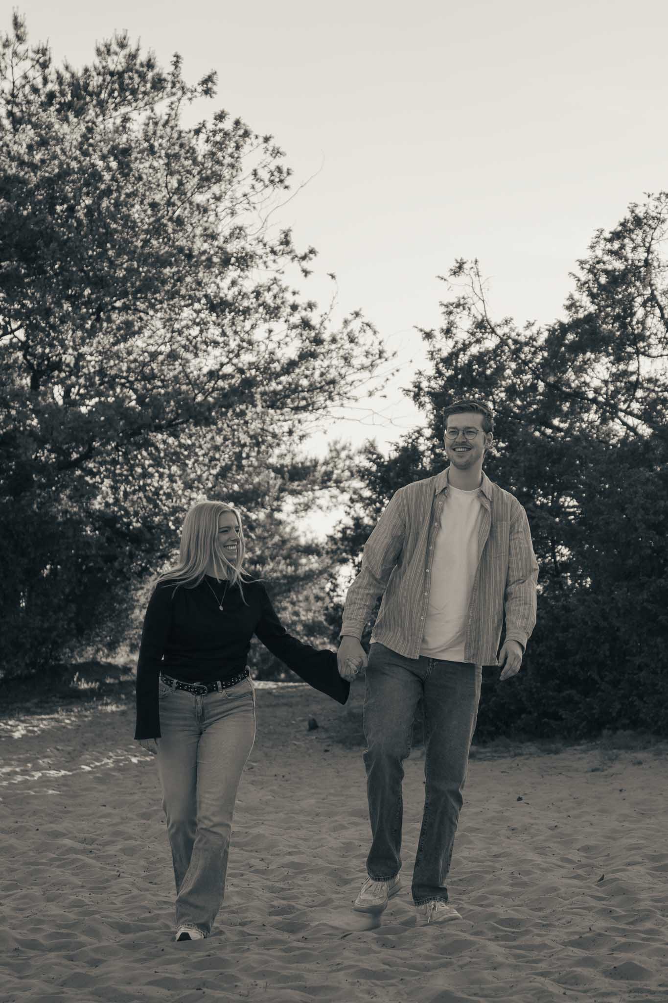 Een koppel loopt hand in hand over een zandvlakte