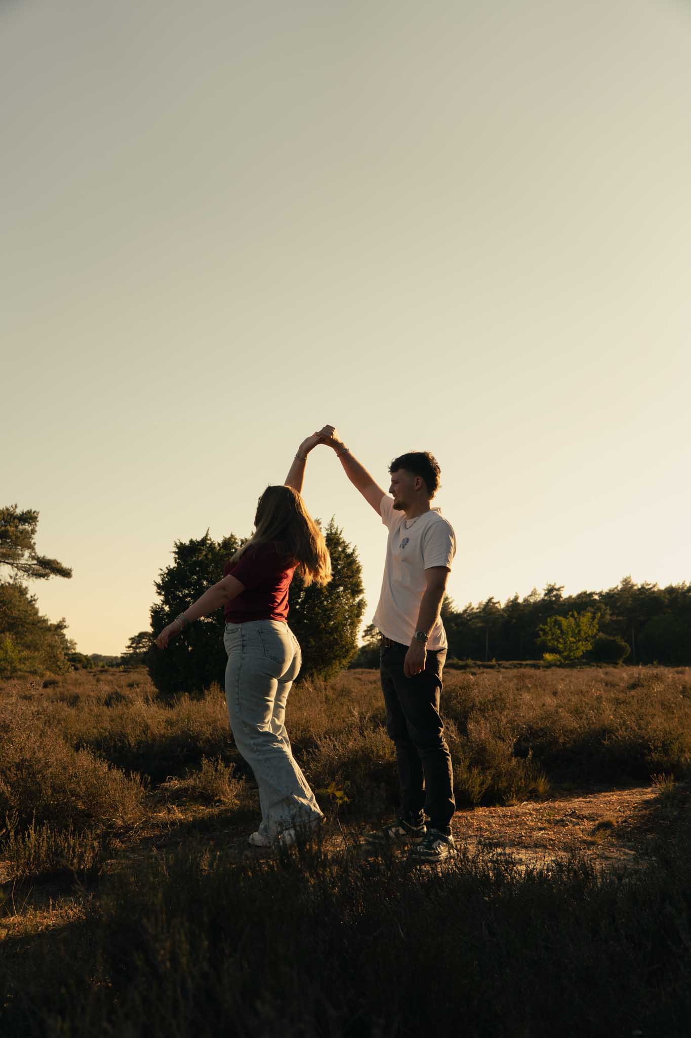 Een man kust een vrouw op haar voorhoofd met een ondergaande zon op de achtergrond